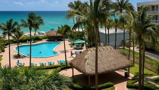 Un resort con piscina, palmeras y vista al océano.