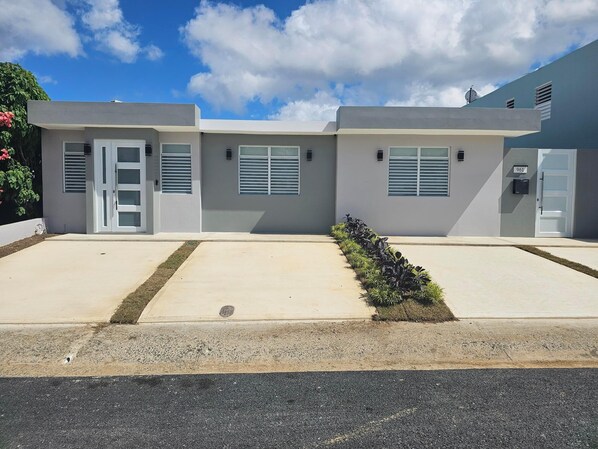 A modern building with a flat roof, large windows, and a gated entrance. - Eduardo's Home (San Juan)