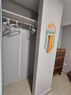 A walk-in closet with a hanging rod and a wooden dresser. - Eduardo's Home (San Juan)