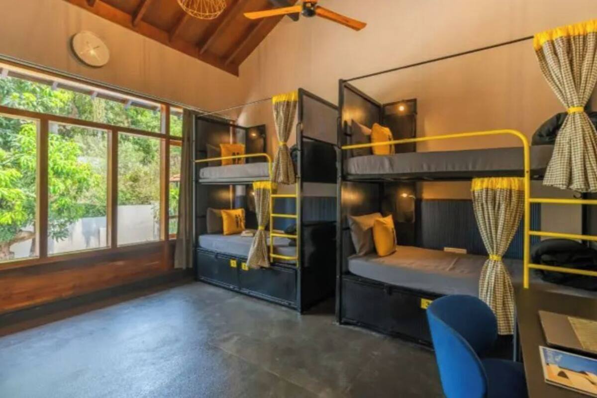 A room with bunk beds, a desk, and a chair.