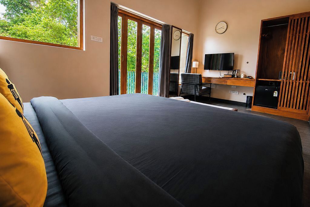 Habitación de hotel con una cama grande, un escritorio con computadora, un televisor y un armario.