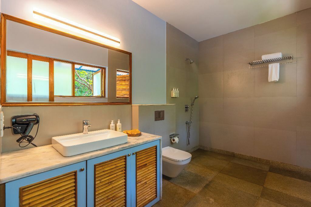 A modern bathroom with a large mirror, a sink, a toilet, and a shower.