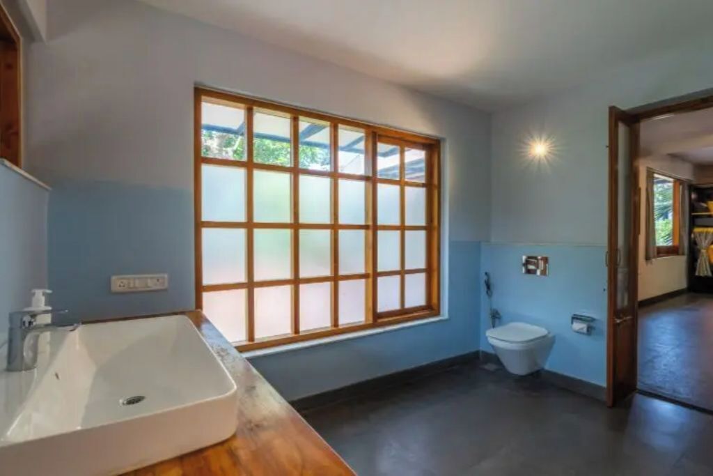 A bathroom with a large window, a sink, and a toilet.