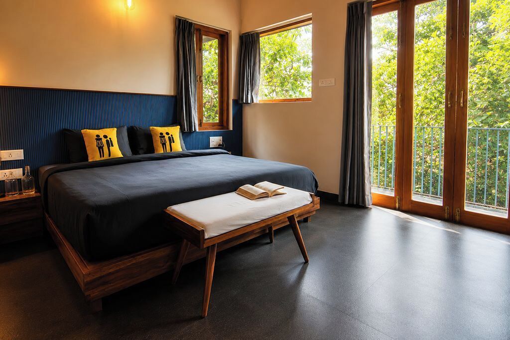 Un dormitorio con una cama grande, una mesita de noche y una ventana con cortinas.