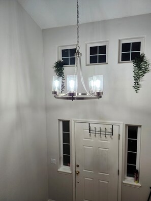 A hallway with a white door, two windows, and a chandelier with lights. - Spacious 5-bedroom house at the heart of Bethany, close to Intel, and Nike (Portland)