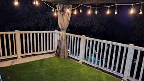 Un espace extérieur doté d’une pelouse artificielle, de rampes blanches et de guirlandes lumineuses.