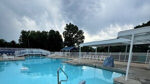 A swimming pool with a white fence, lounge chairs, and a covered area. - Modern Table Rock Cabin - Close to Lake and SDC! (Kimberling City)