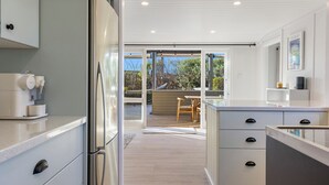 A modern kitchen with a built-in coffee machine, a sliding glass door leading to an outdoor area with a wooden deck and a hammock. - Luxury Hideaway at the Lake (Mangakino)