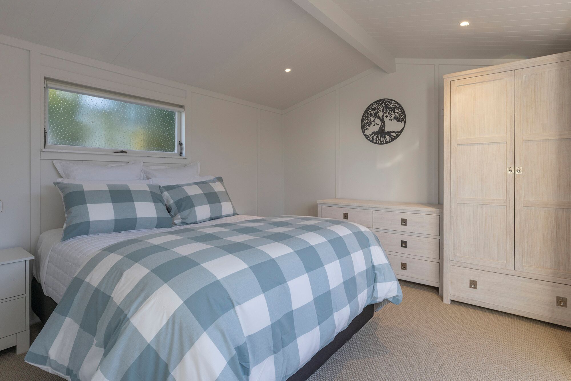 Une chambre à coucher comprenant un lit, une commode, une armoire et un élément décoratif mural.