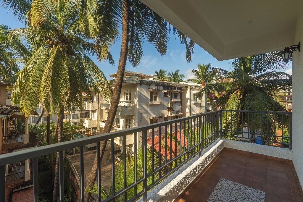 A balcony with a view of a residential area, including buildings and palm trees.