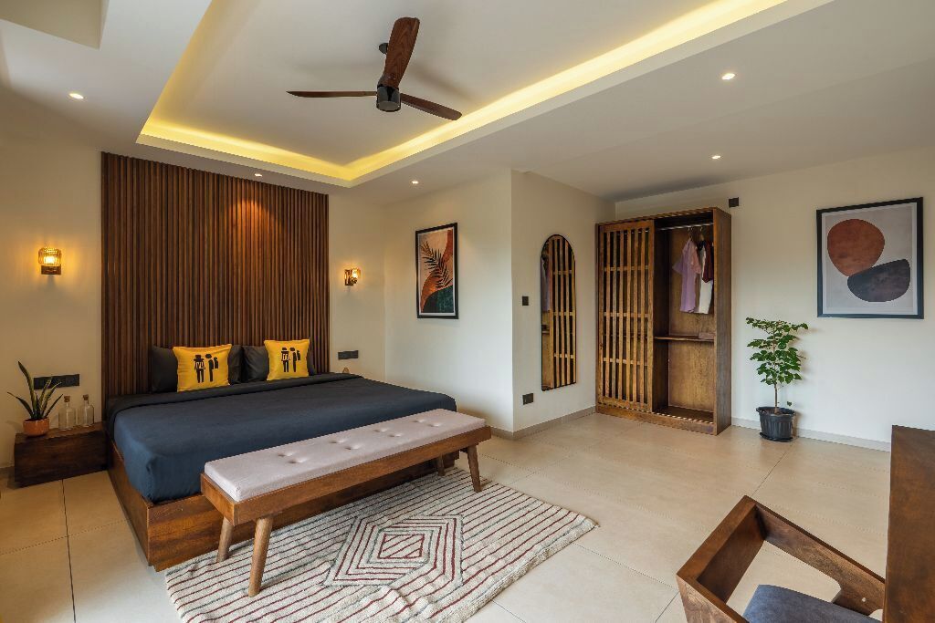 A modern bedroom with a large bed, a ceiling fan, and a wooden wardrobe.