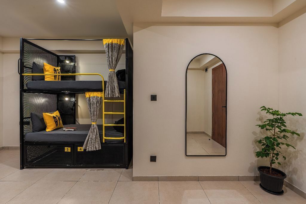 A bunk bed with a ladder, a mirror, and a potted plant in a room with tiled flooring.