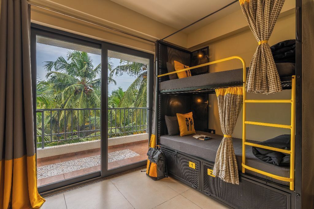 Una habitación con balcón, literas y vistas a palmeras.