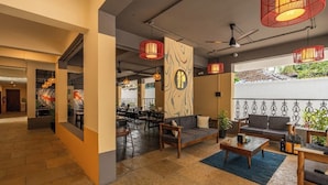A spacious lobby with a seating area, a dining section, and a large window with a view. - The Hosteller Bam Goa Calangute (Calangute)