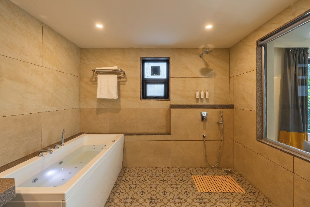 Un bagno moderno con una vasca da bagno ampia, una zona doccia e un piccolo finestrino.