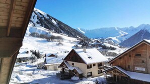 Un pueblo cubierto de nieve en la montaña, con edificios de madera y un cielo azul despejado.