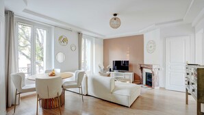 Een ruime woonkamer met een witte bank, een ronde eettafel en een televisie.