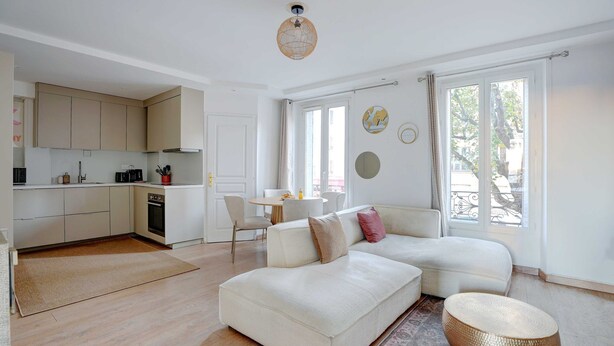 Een moderne woonkamer met een bank, een eettafel en een keukenhoek.