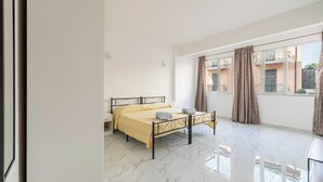 Ein Schlafzimmer mit Bett, einem Fenster mit Vorhängen und einem Balkon.