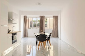 A modern kitchen with a built-in oven and a dining area with a table and chairs. - Central 1bdr/4p Flat in Ventimiglia (Ventimiglia)