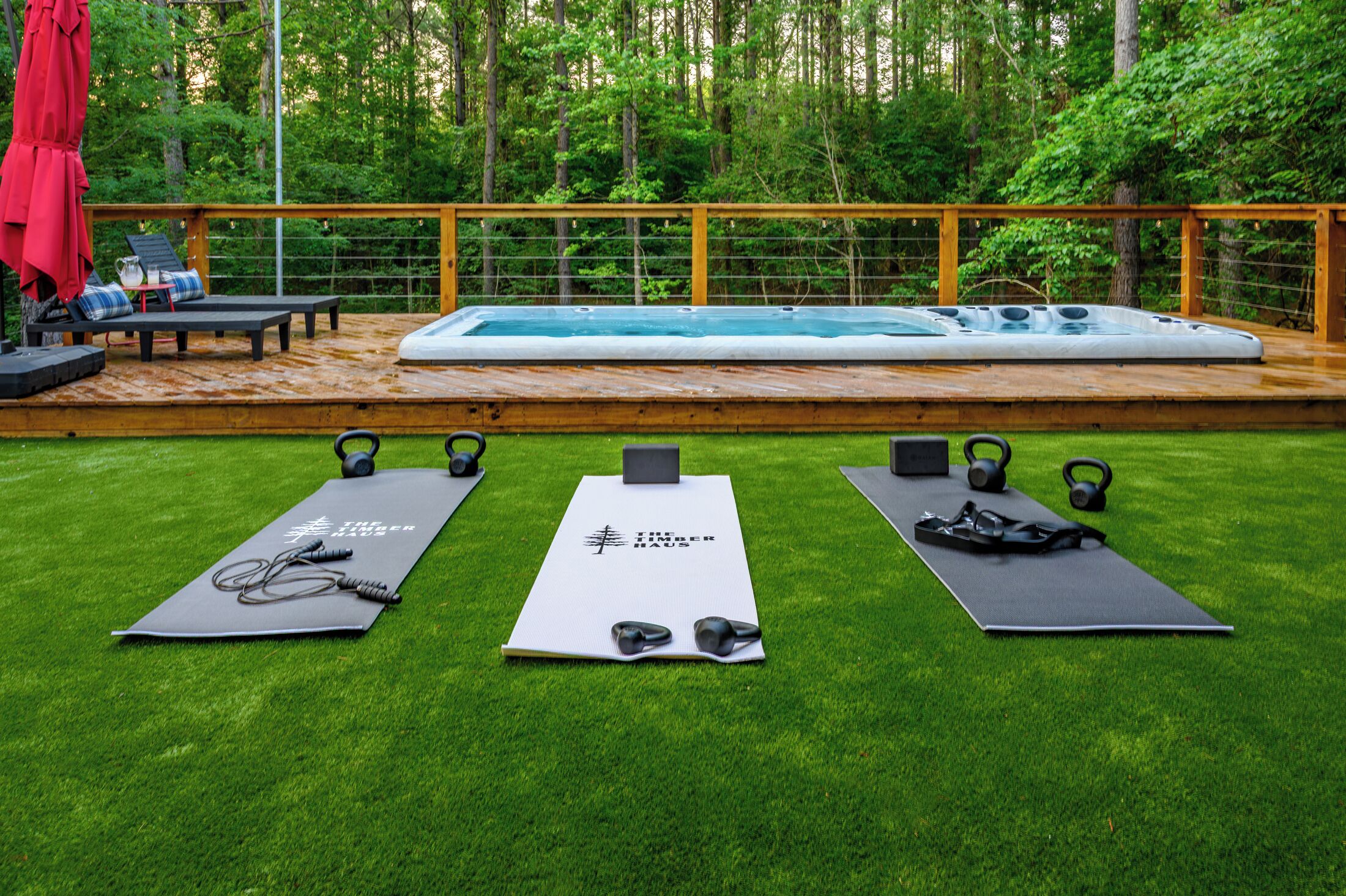 A pool area with a wooden deck, exercise mats, and outdoor furniture.