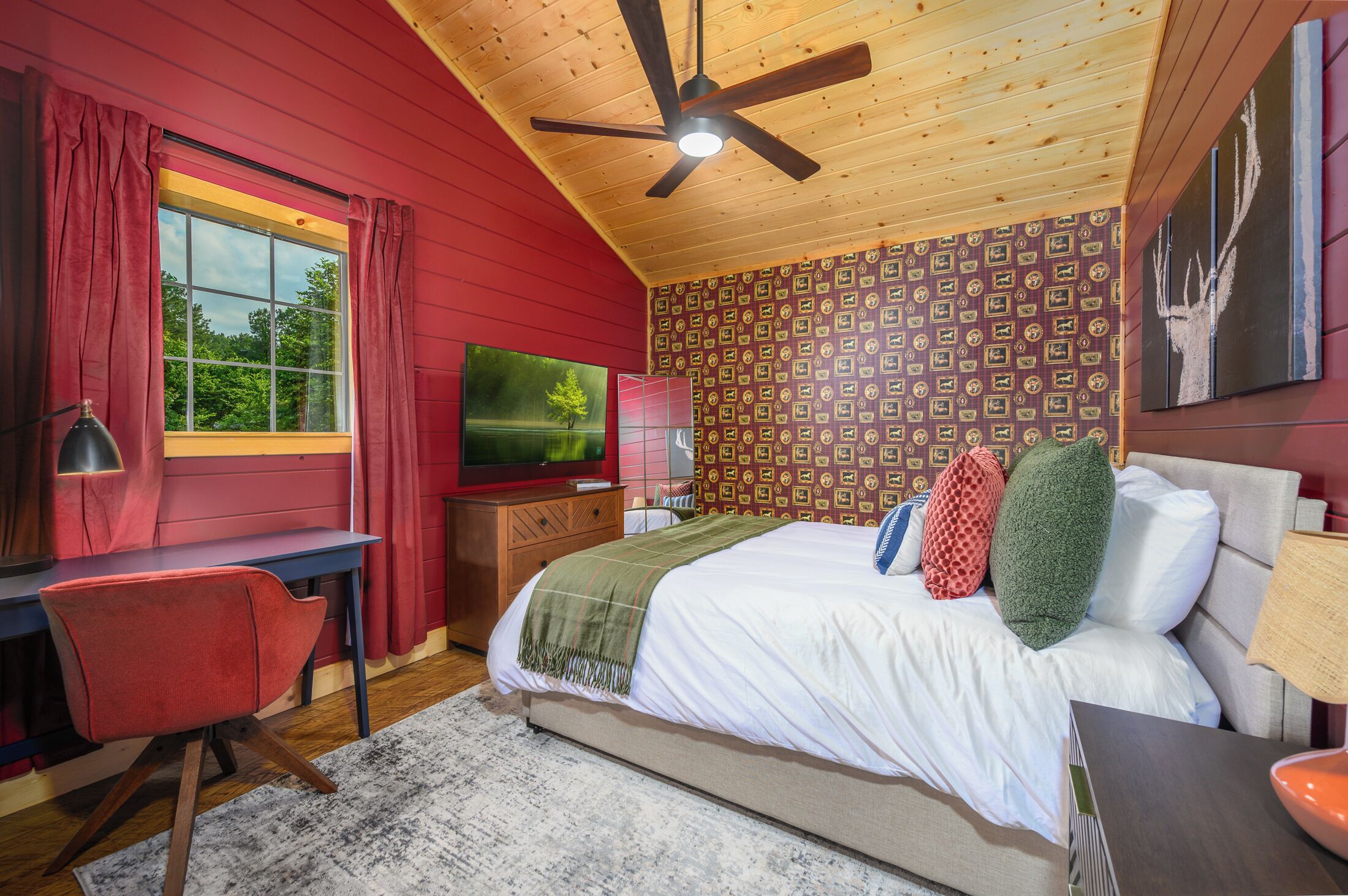 Ein Schlafzimmer mit einem Bett, einem Schreibtisch, einem Sessel, einem Fernseher und einem Deckenventilator.