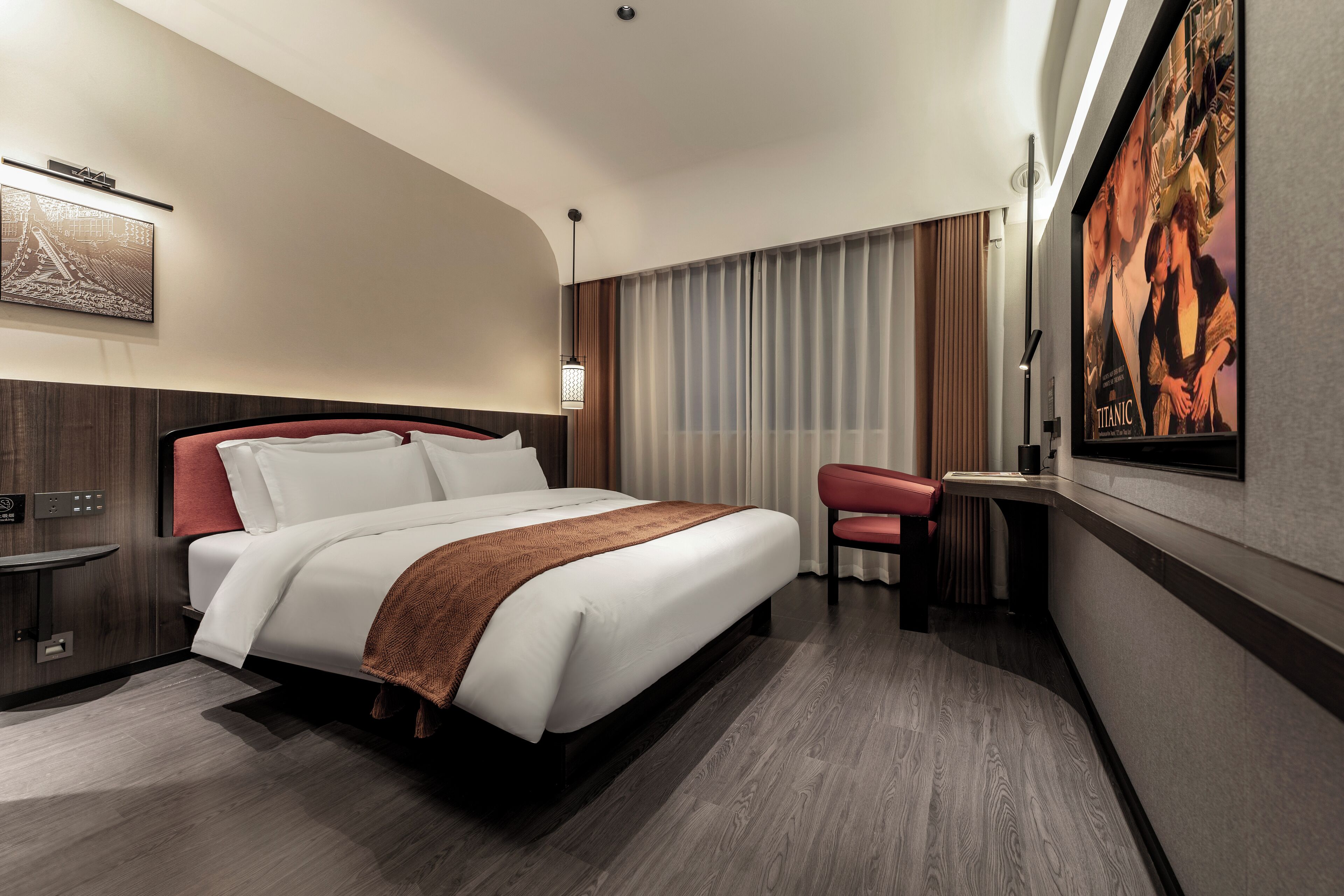 A modern hotel room with a large bed, a desk, and a chair.