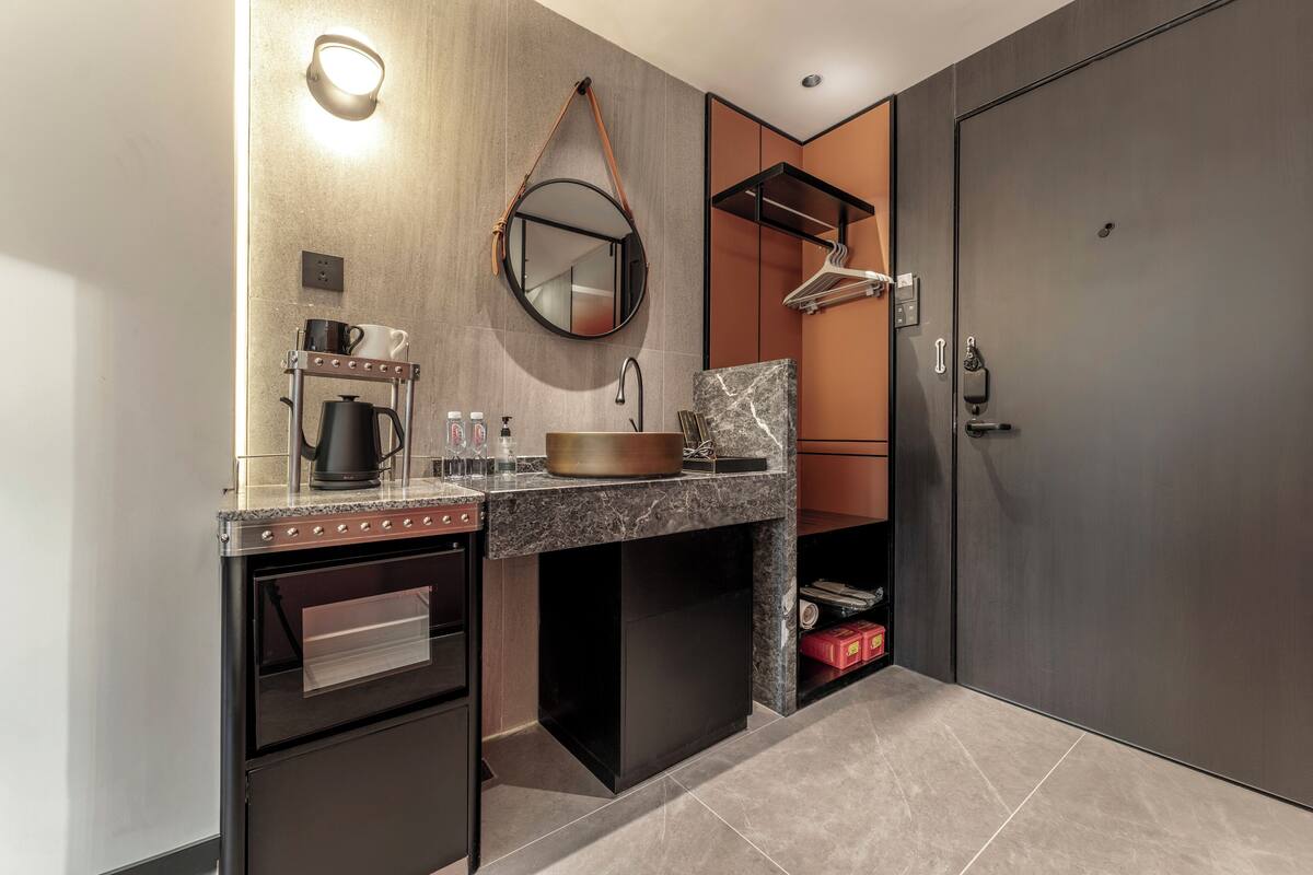 A modern kitchen with a built-in oven, a coffee maker, and a hanging mirror.