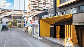 A hotel entrance with a modern design, a visible staircase, and a street view in the background.