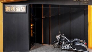 A motorcycle parked in front of a building with a sign that reads "Hotel Kaili." - Kai Li Hotel (Wuhan)