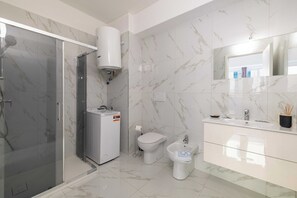 A modern bathroom with a glass shower enclosure, a toilet, a bidet, and a vanity with a mirror. - Posta Suites Flat in Ventimiglia (Ventimiglia)