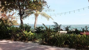 A paved pathway leading to a beach with palm trees and string lights. - Absolute Beachfront Apartment with Kitchen (Boracay)