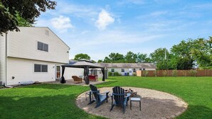 Un jardin avec un patio couvert, du mobilier d’extérieur et un foyer.