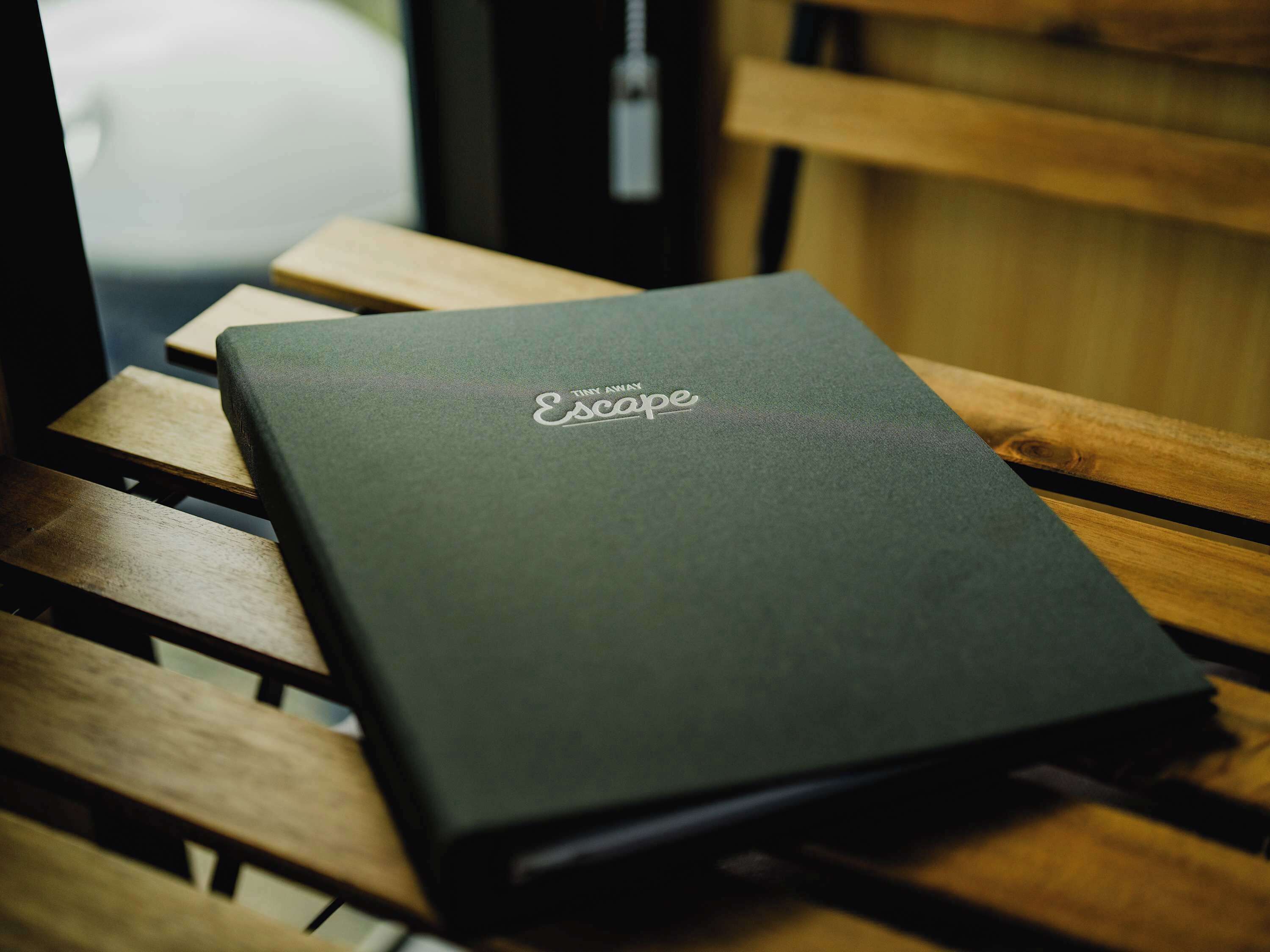 A dark-colored laptop on a wooden bench.