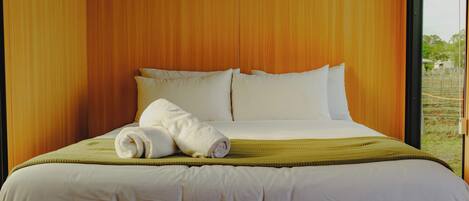 A hotel room with a large bed, white linens, and a view of the outdoors.