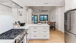 Een moderne keuken met witte kasten, een roestvrijstalen koelkast en een centraal eiland met lades.