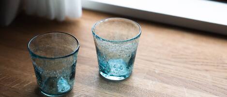 Deux verres d’eau sur une surface en bois, près d’une fenêtre.