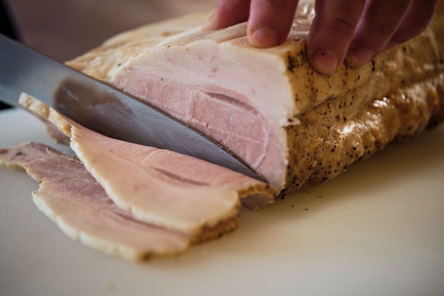Une personne qui découpe une grande pièce de viande sur une planche à découper.
