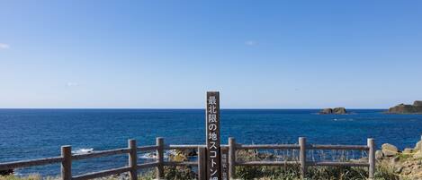 Una valla de madera con un letrero en japonés, con vista al mar y a islas distantes.
