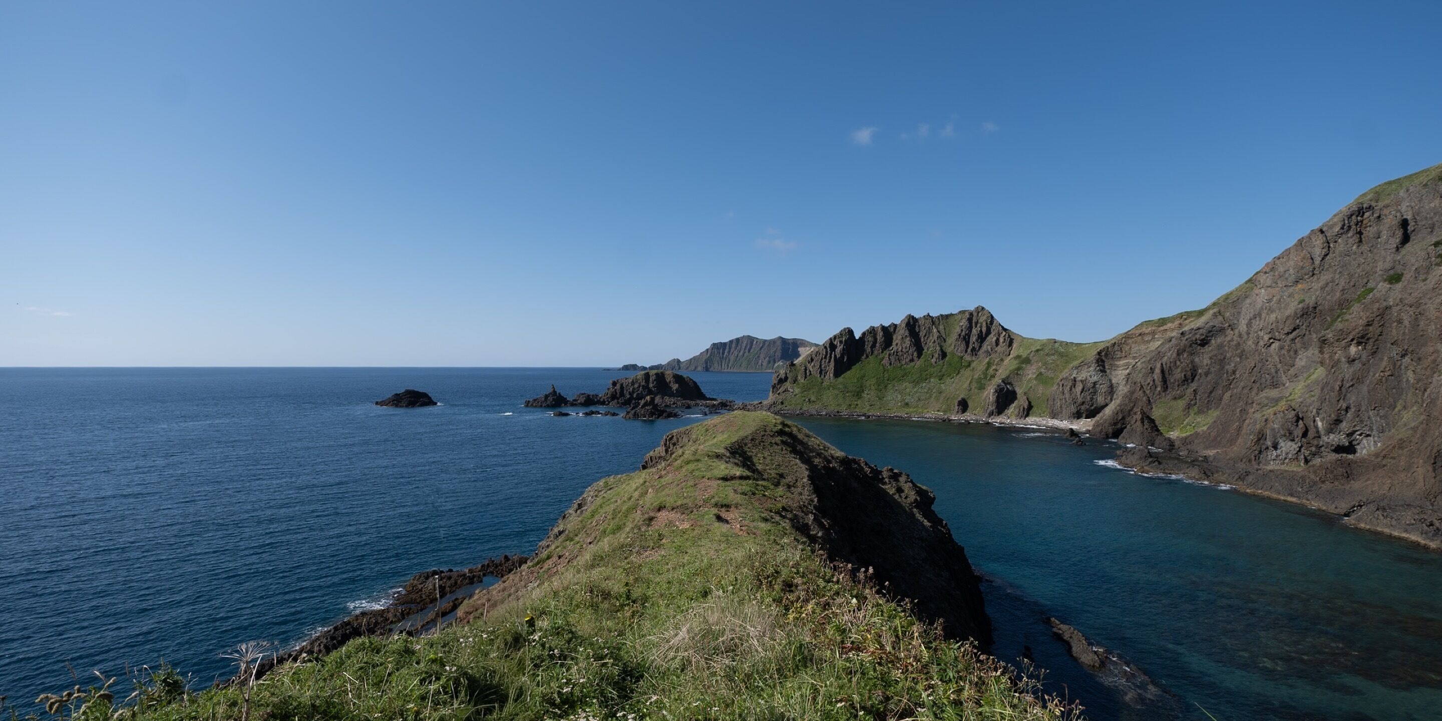 A coastal landscape with rocky cliffs and a clear blue sea.