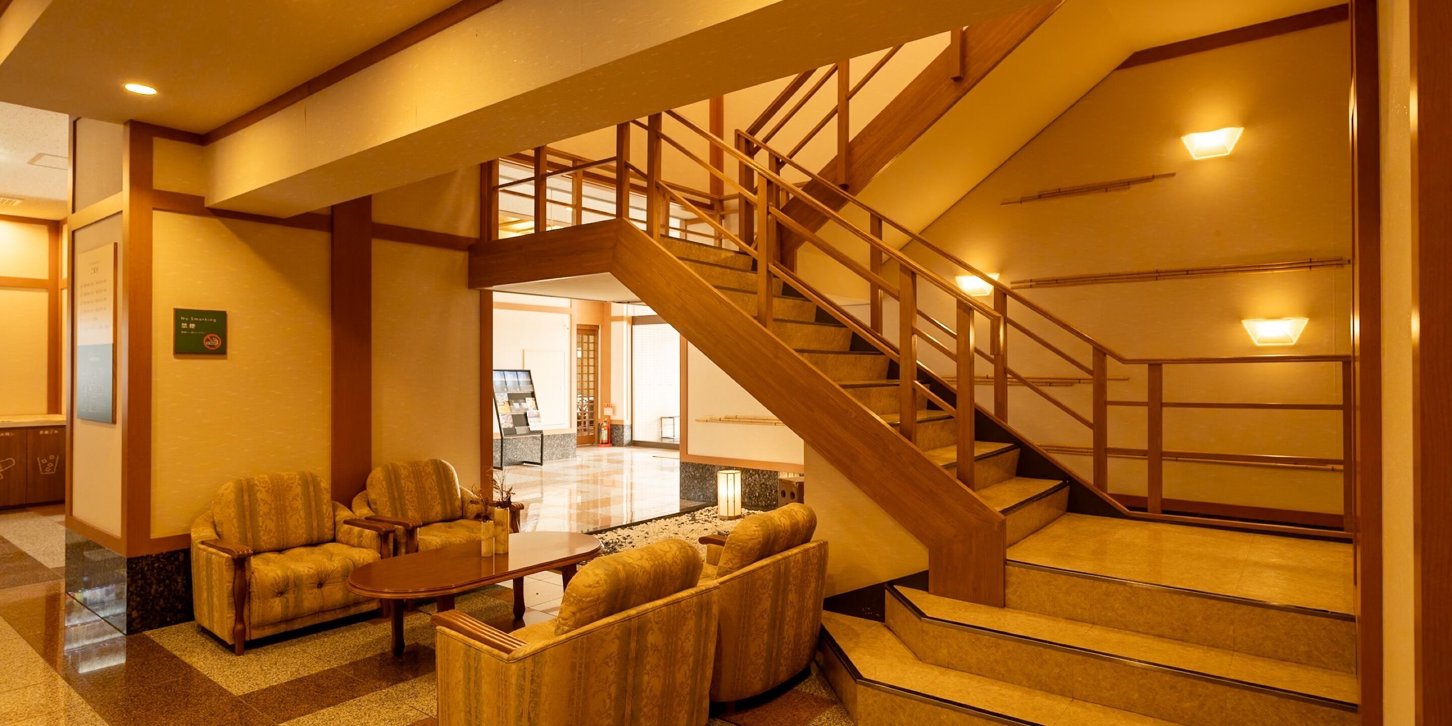 A lobby with a staircase, seating area, and a reception desk.