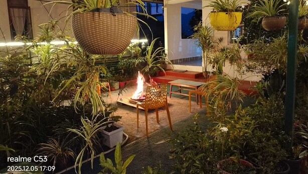 An outdoor patio area with hanging baskets, a fire pit, and potted plants. - Arthur's Inn (Gangtok)