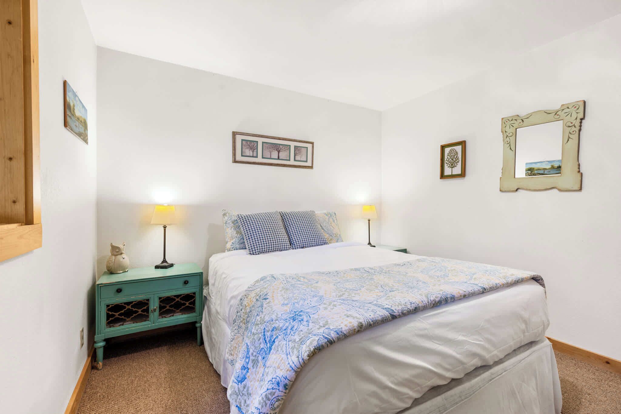 Une chambre à coucher avec un lit, deux lampes de chevet, une table de chevet et un miroir fixé au mur.
