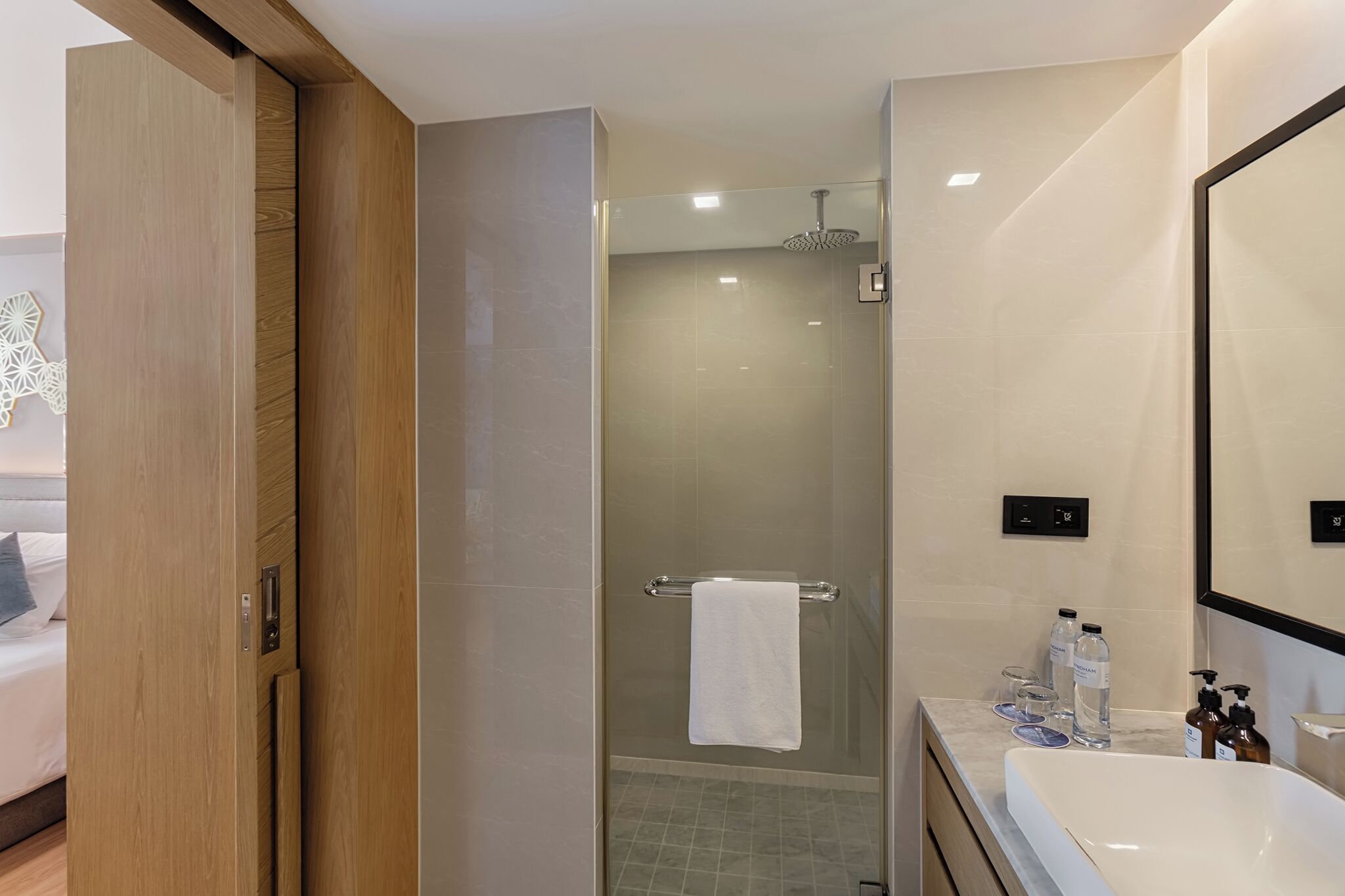 A modern bathroom with a glass-enclosed shower, a large mirror, and a white sink.