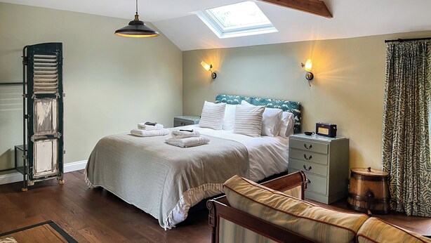 A bedroom with a bed, bedside tables, a bench, a wooden ladder, and a skylight. - The Butterchurn - UK50805 (Cratfield, near Laxfield)