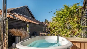 A hot tub in a wooden deck area with a house in the background. - The Butterchurn - UK50805 (Cratfield, near Laxfield)
