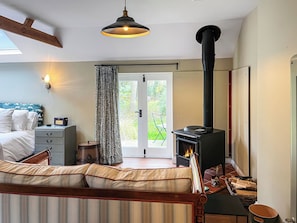 Ein Schlafzimmer mit Bett, einer Couch, einem Kamin, einem Fenster und einer Tür, die nach draußen führt.