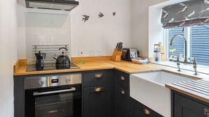 A compact kitchen with a stove, oven, sink, and wooden countertop. - The Butterchurn - UK50805 (Cratfield, near Laxfield)