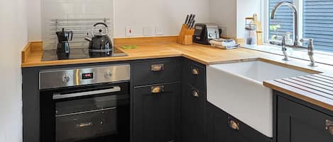 Una cocina compacta con estufa, horno, pileta y encimera de madera.