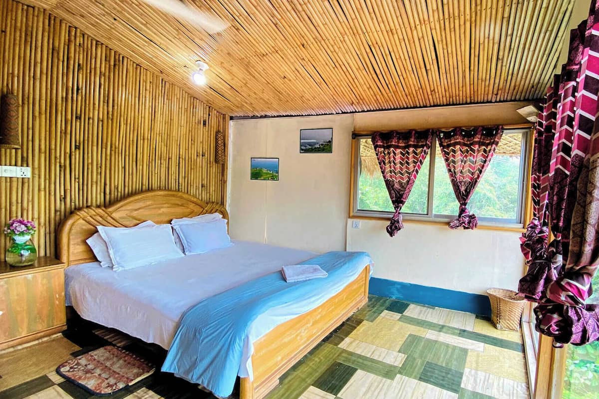 A room with a bed, a window with curtains, a wall with a picture, and a ceiling with a bamboo design.